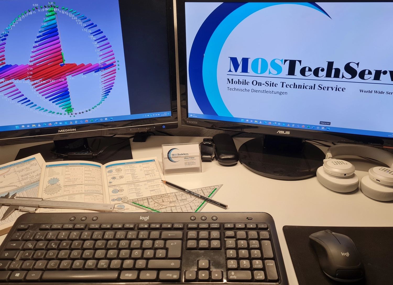 MOSTechServ -  Industrieller, Wartung & Instandhaltung Service -  Ein Arbeitsplatz mit zwei Monitoren, auf denen jeweils ein technisches Diagramm und ein Firmenlogo angezeigt werden. Auf dem Schreibtisch befinden sich eine Tastatur, ein Handbuch und ein Messschieber.